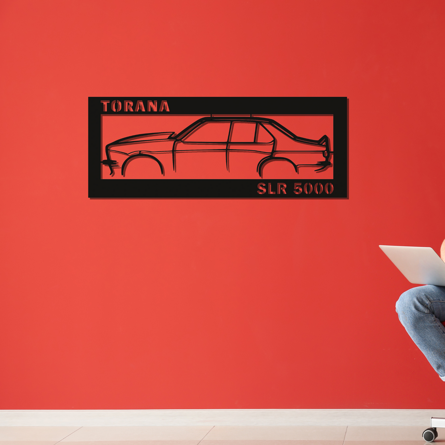 Black silhouette of a car with 'Torana SLR 5000' text on a red wall.